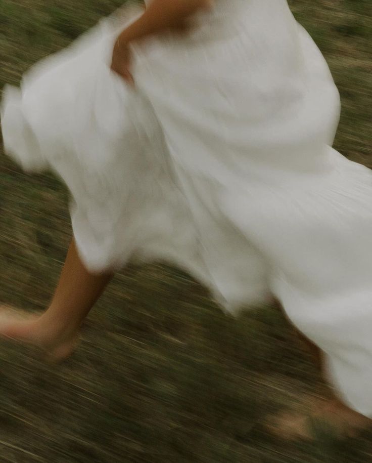 Mujer corriendo con vestido blanco sobre el pasto